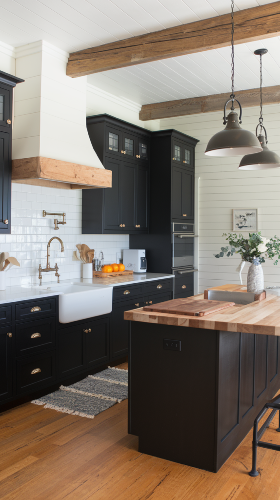 A kitchen with black shaker cabinets, a white subway tile backsplash, and a farmhouse apron-front sink. The walls have shiplap and exposed wooden beams. There are vintage-inspired brushed brass pulls and knobs on the cabinets. Pendant lights in a distressed finish hang above the sink. The countertop is a natural wood butcher block.