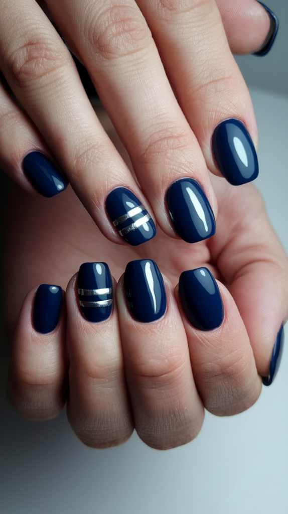 Close-up of hands with navy blue nails featuring silver stripes