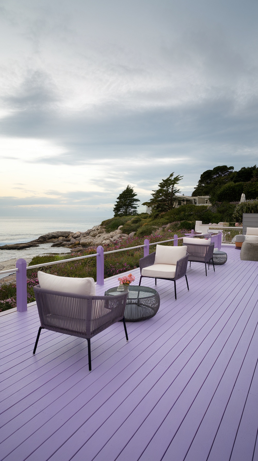 A coastal patio with a muted lavender deck, featuring comfortable seating and a beautiful ocean view.